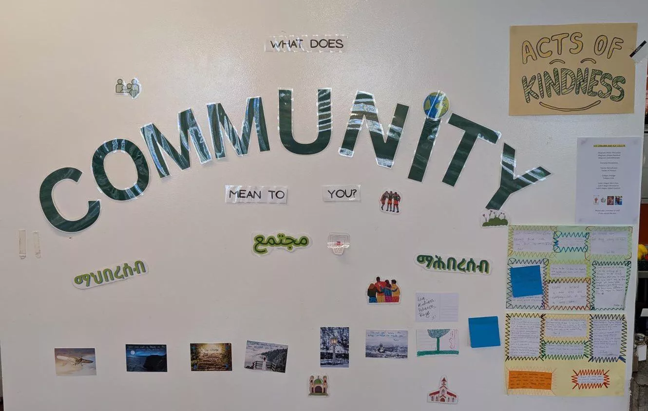 Una pared blanca con grandes letras verdes que forman la palabra «Comunidad». Alrededor hay notas adhesivas y palabras relacionadas con la comunidad.